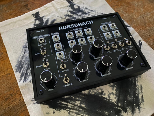 Rorschach black and white video synthesizer resting on a printed fabric bag